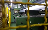 Widok poprzez kraty zabezpieczające na maszynę produkującą firanki